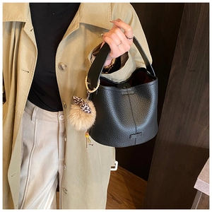 Detail of black pebbled leather bucket bag with leopard bow and fur pompom charm