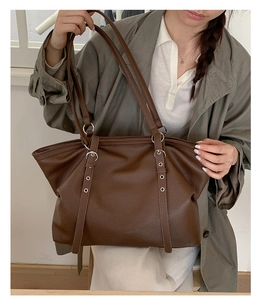 Close-up of brown litchi pattern leather tote bag with silver metal buckles
