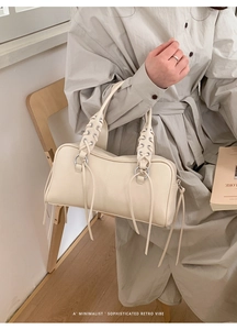 Chic cream shoulder bag featuring metal eyelets and long decorative leather tassels