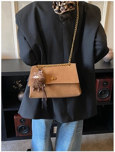Close-up of vintage brown suede messenger bag featuring gold chain and turn-lock clasp