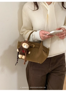 Detail of dark olive suede bucket bag with decorative buckle and cute teddy bear charm