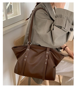 Detail of dark brown lychee leather tote bag with sturdy metal hardware and rivets