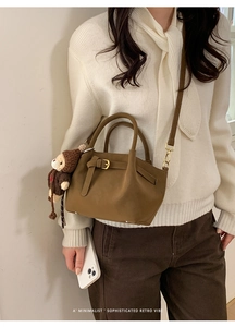 Close-up of retro bucket bag with decorative buckle and cute knit monkey charm