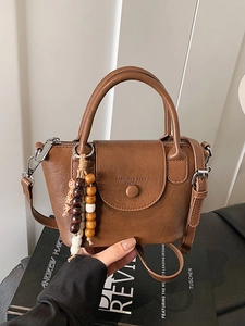 Mini sac à main vintage marron avec pendentif en perles sur un livre de mode