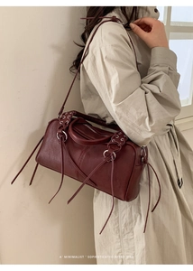Detail of burgundy retro leather Boston bag with silver ring and fringe on trench coat