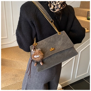 Detail of grey frosted messenger bag with gold chain strap and cute plush charm