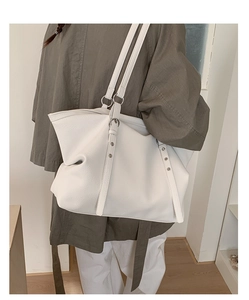 Detail of white lychee textured tote bag with silver rings and rivets on shoulder straps