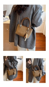 Detail of a brown checkered bucket bag featuring bead tassel and silver hardware