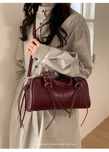Close-up of deep red vintage Boston bag with stylish tassel fringe and rivet details