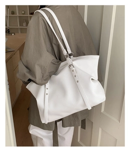 Detail of white tote bag featuring lychee grain leather texture and adjustable strap buckle