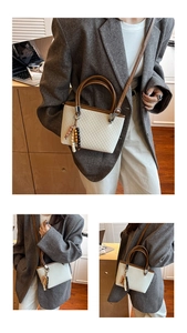 Detail of cream woven bucket bag with brown leather handles and beaded charm accessory