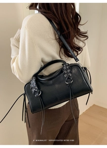 Detail showing retro black leather crossbody bag with silver eyelets and long tassel straps