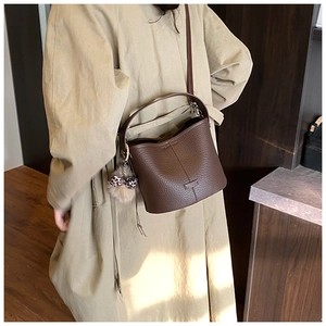 Detail of coffee brown lychee pattern bucket bag with a leopard bow plush charm accessory