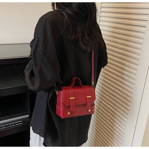 Detail of dark red vintage crossbody bag with gold metallic hardware and top handle strap