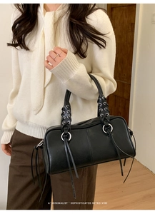 Detail of vintage black baguette bag with silver eyelets and long leather tassels