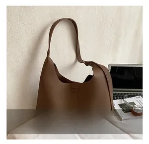 Detailaufnahme einer braunen Hobo-Tasche aus genarbtem Leder mit breitem Schultergurt