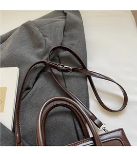 Detail of dark brown leather handbag with silver metal buckle and adjustable strap