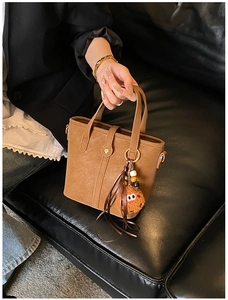 Detailansicht der braunen Wildleder-Beuteltasche mit Goldbeschlägen und Keks-Anhänger