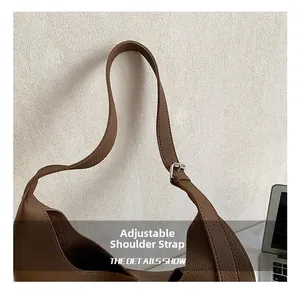 Detailaufnahme des verstellbaren Lederriemens mit Silberschnalle an brauner Tasche