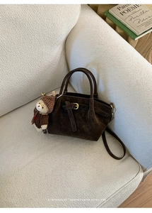 Close-up of a vintage brown suede bucket bag with leather strap and cute bear charm