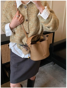 Brown lychee leather bucket bag styled with leopard fur ball charm on shoulder strap