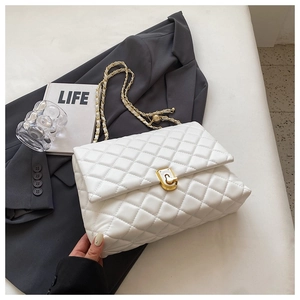 Close-up of white quilted leather bag with gold twist lock and adjustable chain strap