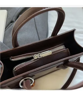 Close-up of smooth silver metal zipper and hardware on deep brown leather handbag