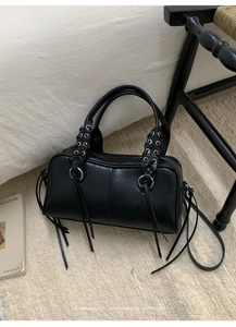 Detail of black motorcycle bag featuring woven rope handles and long leather tassels