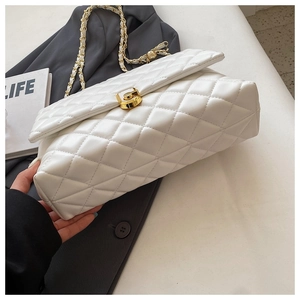 Close-up of white quilted leather texture and gold metal clasp on a chain crossbody bag