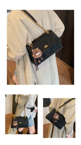 Detail of black crossbody bag with gold chain strap and a unique brown plush eyeball charm