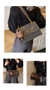 Detail of grey suede messenger bag with gold chain strap and cute furry monster charm