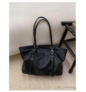 Detail of black large capacity tote bag with lychee texture and silver metal ring accents