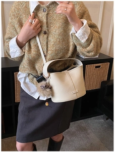 Close-up of beige leather bucket bag with leopard print pom-pom and tassel detail