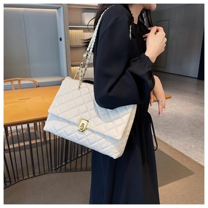 Detail of white quilted crossbody bag with golden chain strap and twist lock on model