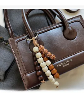 Detailed close-up of a brown leather handbag featuring retro decorative beaded tassels