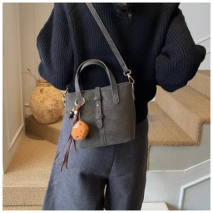 Détail du sac seau en daim gris foncé avec charm bonhomme de pain d'épices et bandoulière