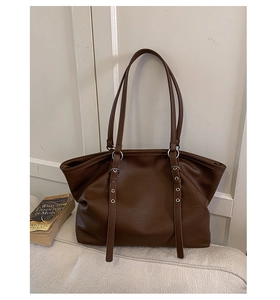 Close-up of brown lychee grain faux leather tote bag with silver rivets on straps