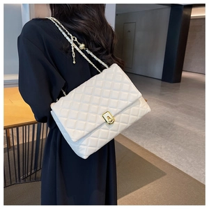 Detail of ivory quilted leather bag showing gold twist lock and woven chain strap
