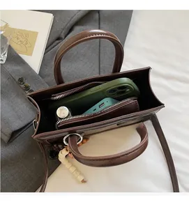 Spacious interior of dark brown baguette bag holding a smartphone and power bank