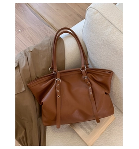 Detailed macro view of caramel brown leather tote featuring soft pebble grain texture