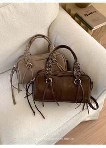 Detail of vintage leather boston bag featuring studded straps and long leather tassels