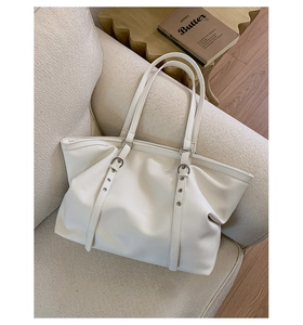 Detailed view of large off-white tote bag with litchi texture and metal buckle accents