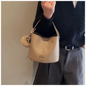 Detail of beige lychee leather bucket bag with leopard print and faux fur pompom charm