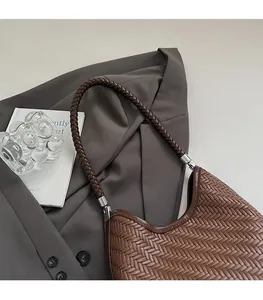 Detailed view of woven brown leather shoulder bag with thick strap and silver hardware