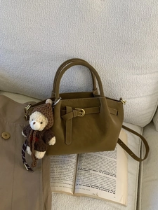 Vintage caramel brown shoulder bag with a cute bear charm on a warm lifestyle background