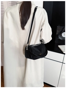 Model wearing a black nylon crossbody bag with silver zippers and adjustable strap