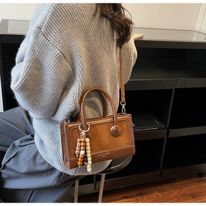 Détail du sac à main vintage marron foncé avec patchwork cuir et breloque ethnique