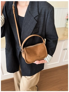 Detail of caramel brown suede handbag showing fine stitching and metal zipper