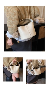 Detail of off-white lychee pattern leather bucket bag with plush pompom and stone charms