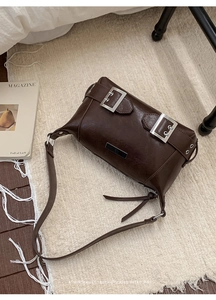 Detail of chocolate retro tote bag with glossy finish and silver buckle decorations